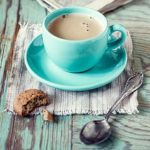 Xícara azul-turquesa com chocolate quente e biscoito