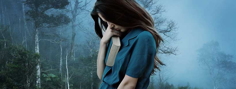 Moça triste segurando livro no campo com vento Alessandra Cerri - Sentimentos Negativos